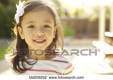 Stock Image - Mixed race girl smiling outdoors. Fotosearch