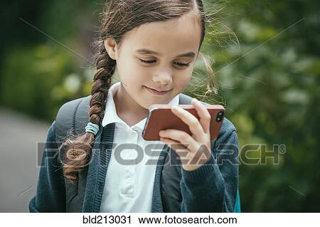 Stock Image - Mixed race girl using cell phone outdoors. Fotosearch