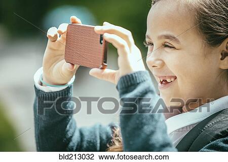 Stock Image - Mixed race girl using cell phone outdoors. Fotosearch
