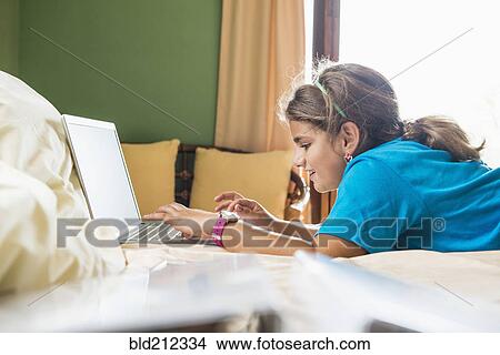Mixed race girl using laptop on bed View Large Photo Image Picture - Mixed race girl using laptop on bed. Fotosearch