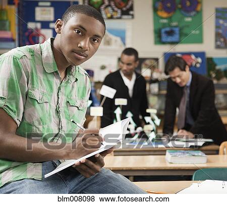 Stock Photo - Mixed race high school student writing in notebook. Fotosearch