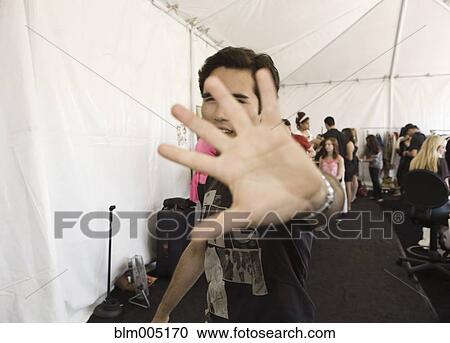 Stock Image - Mixed race man blocking camera in dressing room. Fotosearch