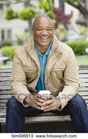 Mixed race man drinking coffee in park View Large Photo Image Stock Image - Mixed race man drinking coffee in park. Fotosearch