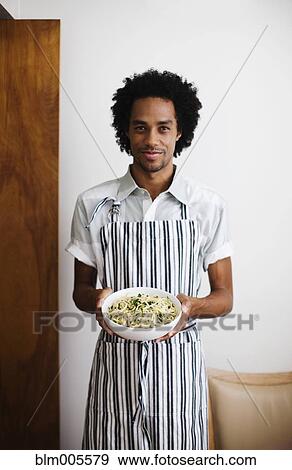 Mixed race man holding bowl of pasta View Large Photo Image Stock Photo - Mixed race man holding bowl of pasta. Fotosearch