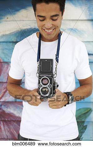 Stock Photo - Mixed race man holding old-fashioned camera. Fotosearch