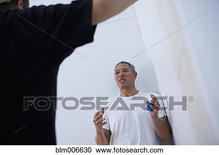 Mixed race man in racquetball court talking to friend View Large Photo Image Stock Image - Mixed race man in racquetball court talking to friend. Fotosearch