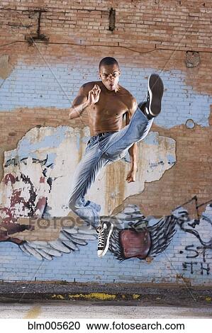 Stock Image - Mixed race man jumping in mid-air. Fotosearch