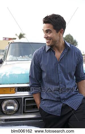 Stock Image - Mixed race man leaning against truck. Fotosearch