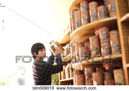 Mixed race man lifting canister from shelf in shop View Large Photo Image Stock Photo - Mixed race man lifting canister from shelf in shop. Fotosearch