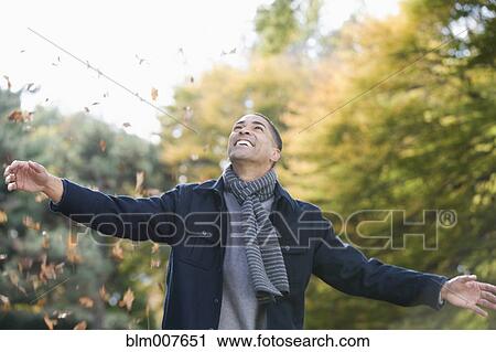 Mixed race man playing in autumn leaves in park View Large Photo Image Stock Image - Mixed race man playing in autumn leaves in park. Fotosearch