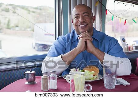 Stock Image - Mixed race man praying in diner. Fotosearch