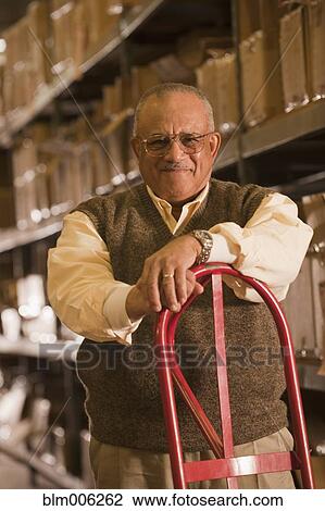 Mixed race man with hand truck in warehouse View Large Photo Image Stock Image - Mixed race man with hand truck in warehouse. Fotosearch