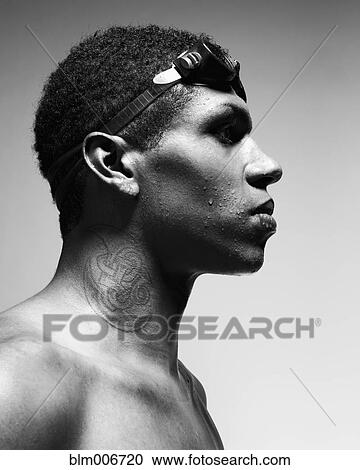 Stock Image - Mixed race man with tattoo wearing swimming goggles. Fotosearch