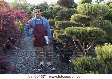 Stock Image - Mixed race man working in garden nursery. Fotosearch