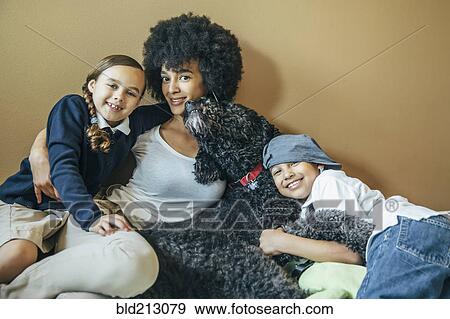 Stock Photo - Mixed race mother and children hugging dog. Fotosearch