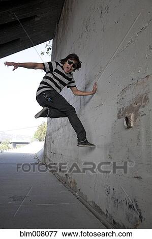 Mixed race teenage boy jumping off wall View Large Photo Image Stock Photo - Mixed race teenage boy jumping off wall. Fotosearch