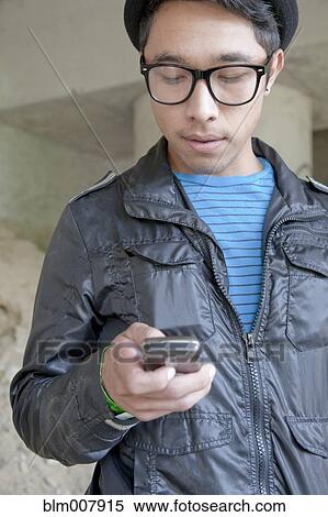 Stock Photography - Mixed race teenage boy text messaging with cell phone. Fotosearch