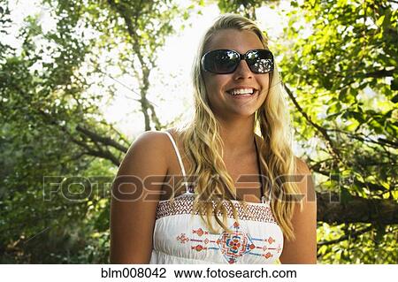 Stock Image - Mixed race teenage girl smiling under tree. Fotosearch