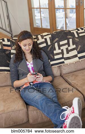 Mixed race teenager listening to mp3 player in living room View Large Photo Image Picture - Mixed race teenager listening to mp3 player in living room. Fotosearch