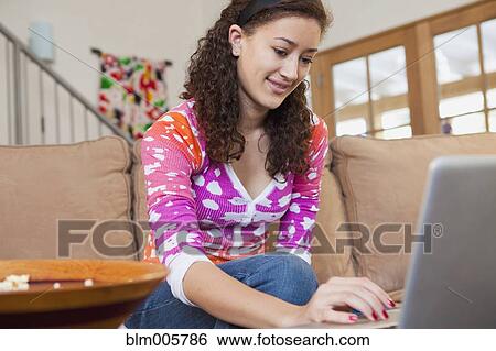 Mixed race teenager typing on laptop in living room View Large Photo Image Stock Photograph - Mixed race teenager typing on laptop in living room. Fotosearch