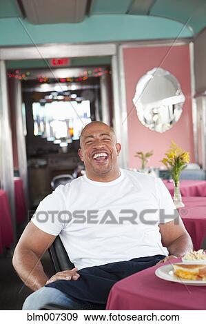 Stock Photo - Mixed race waiter laughing in restaurant. Fotosearch
