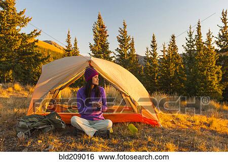Stock Photograph - Mixed race woman camping in rural landscape. Fotosearch