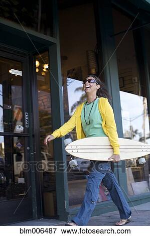 Stock Photo - Mixed race woman carrying skateboard. Fotosearch