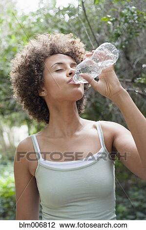 Stock Image - Mixed race woman drinking water. Fotosearch