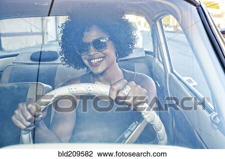Stock Image - Mixed race woman driving vintage car. Fotosearch