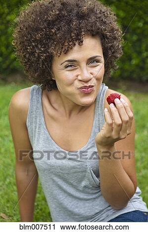 Stock Image - Mixed race woman eating strawberry. Fotosearch