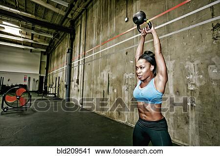 Stock Image - Mixed race woman exercising in gym. Fotosearch