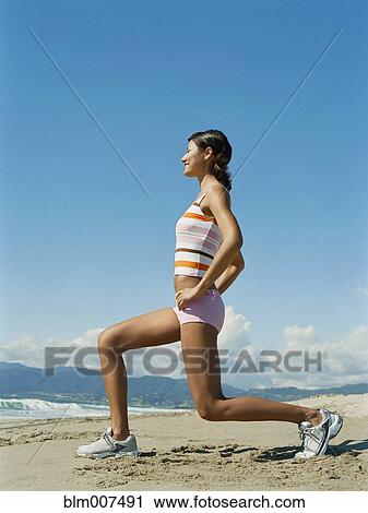 Stock Image - Mixed race woman exercising on beach. Fotosearch