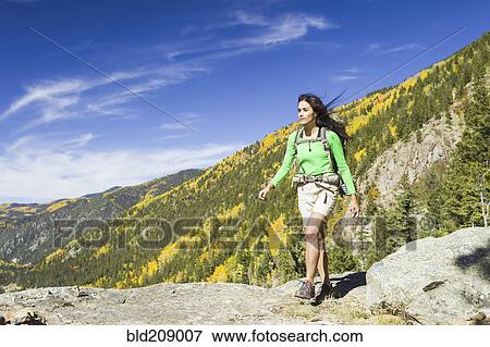Stock Photo - Mixed race woman hiking on rocky hilltop. Fotosearch