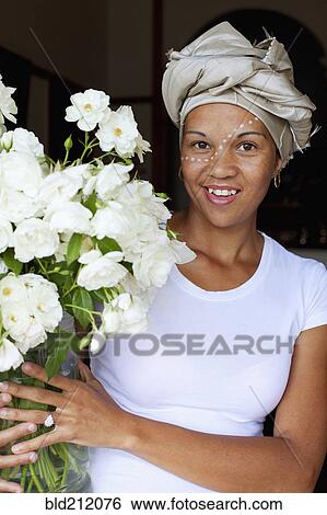 Stock Photograph - Mixed race woman holding bouquet of flowers. Fotosearch