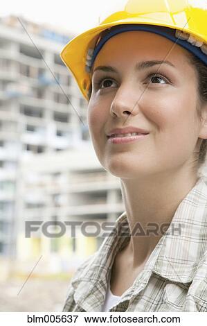 Stock Photo - Mixed race woman in hard-hat on construction site. Fotosearch