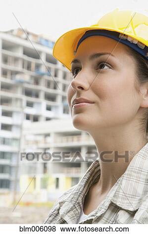Stock Photo - Mixed race woman in hard-hat on construction site. Fotosearch