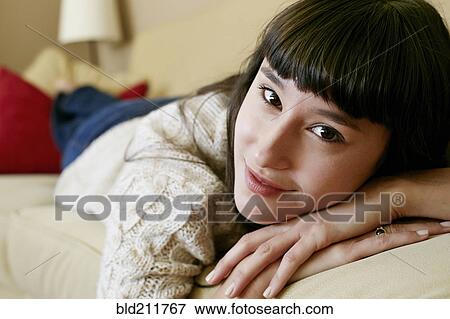 Stock Photo - Mixed race woman laying on sofa. Fotosearch