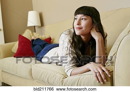 Stock Photograph - Mixed race woman laying on sofa. Fotosearch