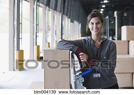Mixed race woman leaning on box at warehouse loading dock View Large Photo Image Stock Photo - Mixed race woman leaning on box at warehouse loading dock. Fotosearch