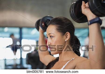 Stock Image - Mixed race woman lifting weights. Fotosearch