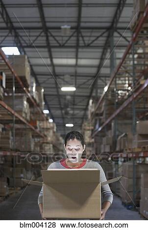 Mixed race woman looking at light inside box in warehouse View Large Photo Image Stock Photo - Mixed race woman looking at light inside box in warehouse. Fotosearch