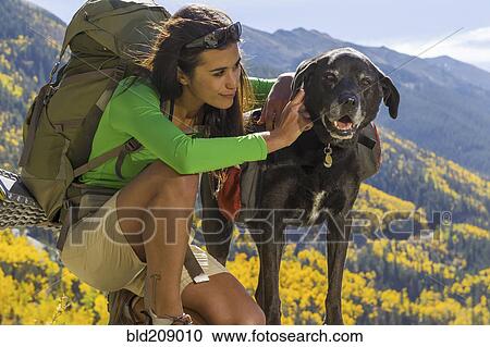 Mixed race woman petting dog on hilltop View Large Photo Image Stock Image - Mixed race woman petting dog on hilltop. Fotosearch