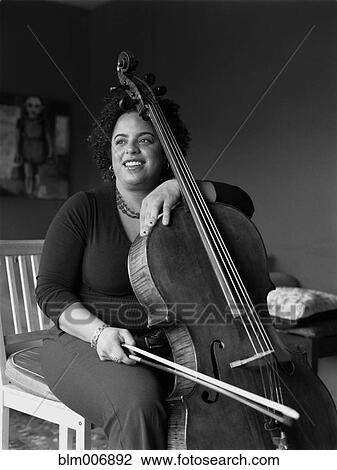 Stock Image - Mixed race woman playing cello. Fotosearch
