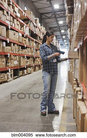 Stock Photography - Mixed race woman scanning box in warehouse. Fotosearch