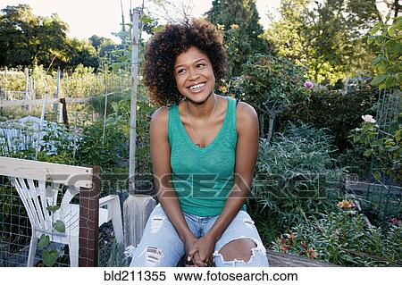 Stock Photography - Mixed race woman sitting in garden. Fotosearch