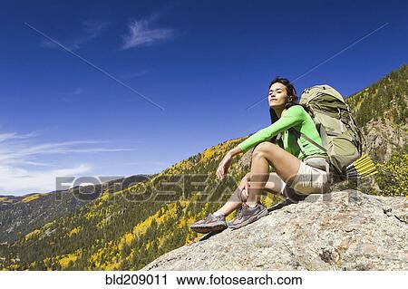 Stock Image - Mixed race woman sitting on rock. Fotosearch