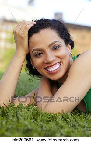 Stock Image - Mixed race woman smiling in grass. Fotosearch