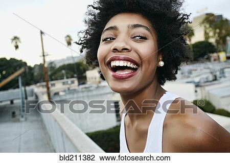 Stock Image - Mixed race woman smiling on urban rooftop. Fotosearch