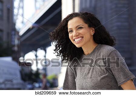 Stock Photo - Mixed race woman smiling under urban bridge. Fotosearch