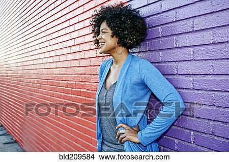 Mixed race woman standing by colorful wall View Large Photo Image Picture - Mixed race woman standing by colorful wall. Fotosearch